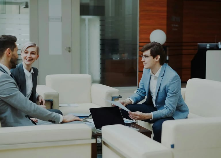 Professional business consultants in a corporate lounge discussing financial strategy documents.