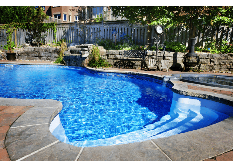 Sparkling blue kidney shaped pool set in a beautifully landscaped backyeard.