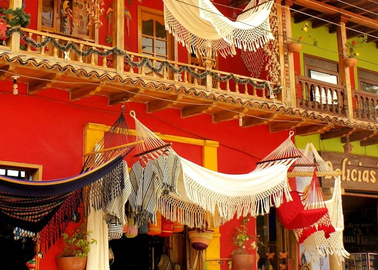 Hamacs colombiens tissés à la main exposés devant un bâtiment colonial rouge coloré dans un marché