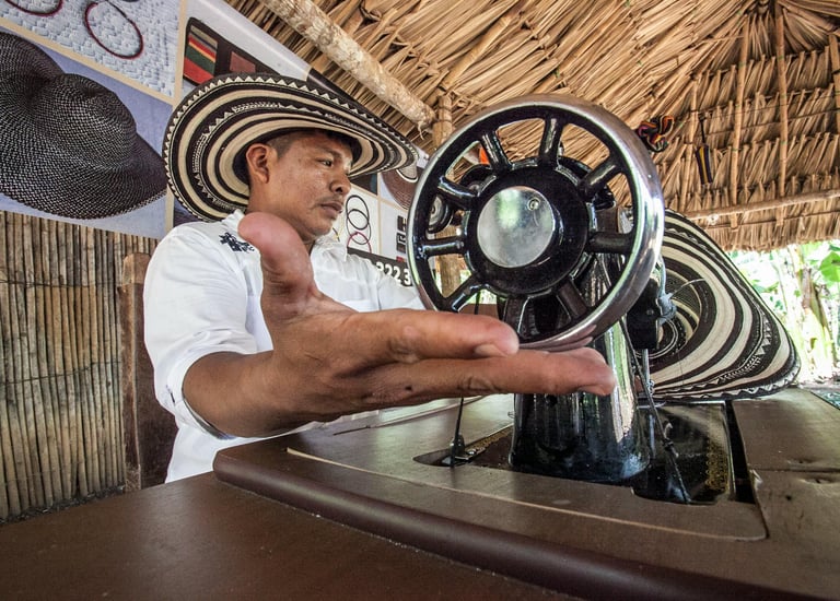 Un artisan portant un sombrero vueltiao utilise une machine à coudre vintage pour créer des chapeaux