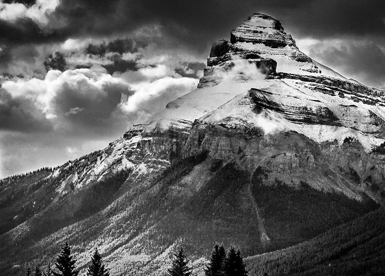 Charity Mountain in the Canadian Rocky Mountains, showcasing it's rugged snow covering and a dramtic sky