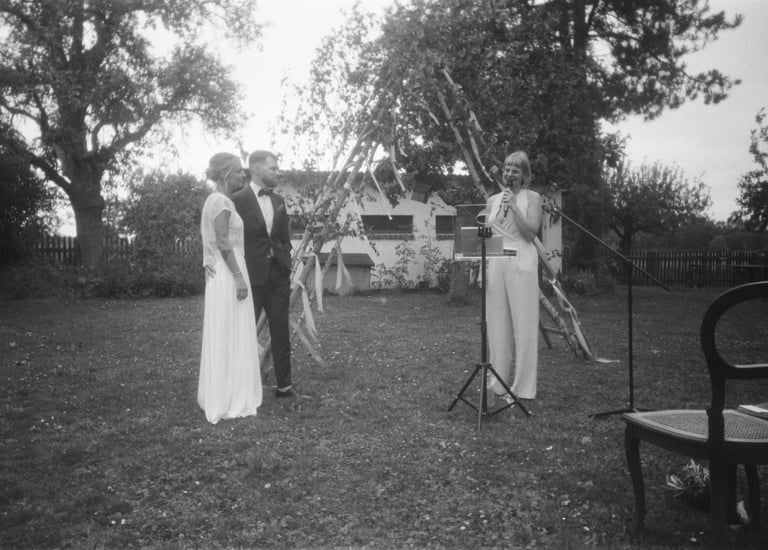 Traurednerin Silke steht bei einer freien Trauung im Freien und spricht vor den Gästen eine persönliche Zeremonierede.