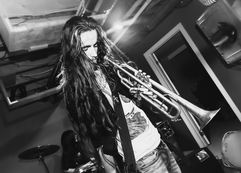 Black and white camus holding a trumpet, looking down