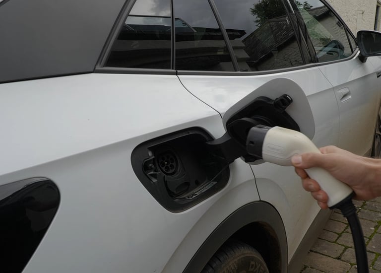 a person plugging in a Tesla EV car to charge from Excess Solar