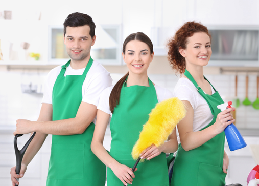 a group of people in green aprons holding cleaning supplies