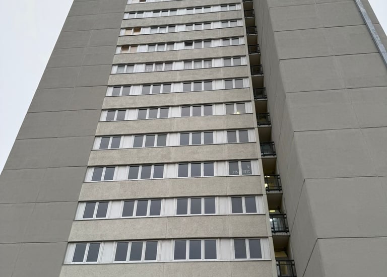 Unrenovierte Hochhausfassade mit einheitlich grauem Putz – Hebestreit Generalunternehmer