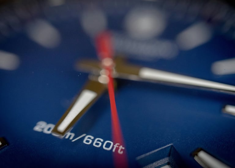 a close up of a blue watch face with a red line on the face of