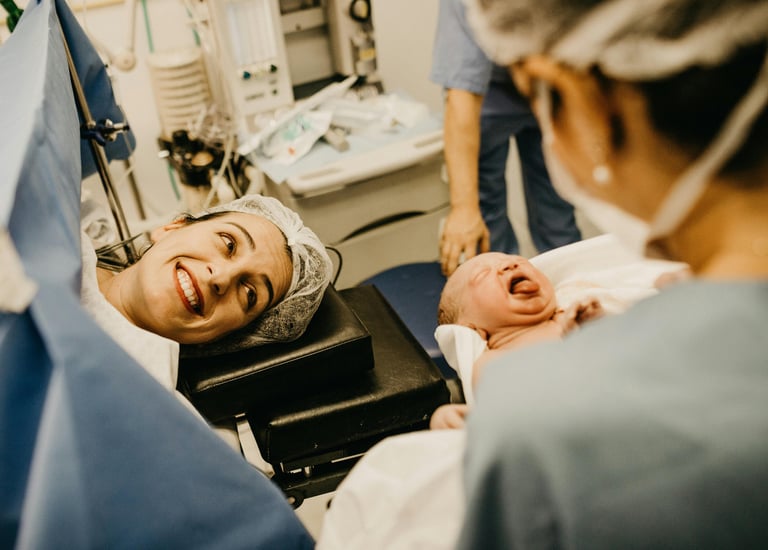 happy mother post delivery smiling seeing her baby in the doctor's hand