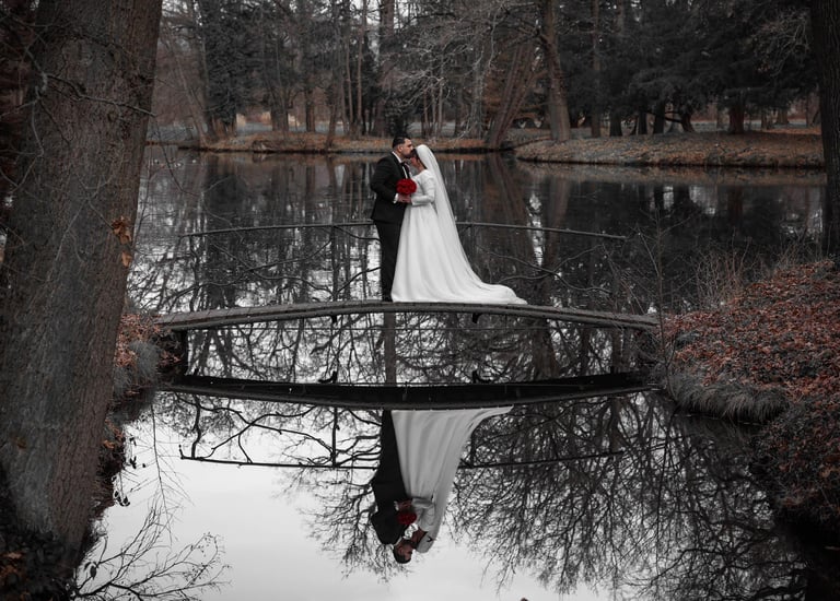 a bride and groom standing on a bridge over a pond