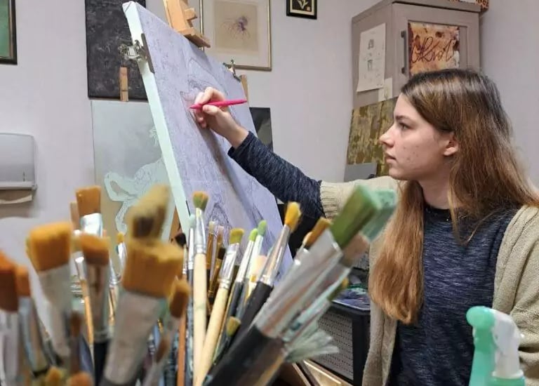 a woman is painting a picture on a easel