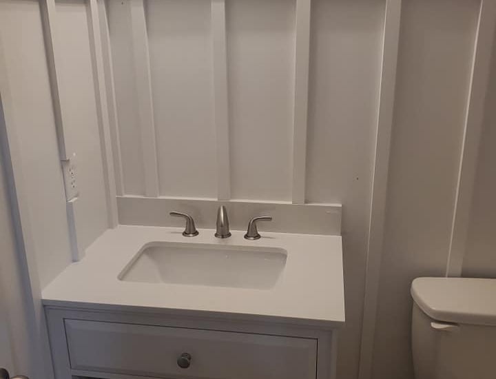 Modern white bathroom vanity with integrated sink and board and batten wall paneling.