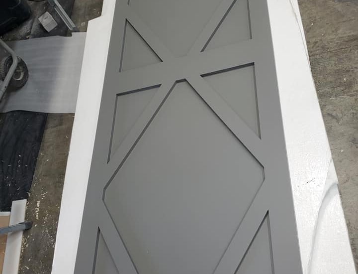 Custom grey sliding barn door with a geometric diamond pattern panel in a workshop.