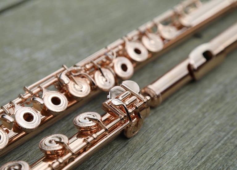 un flûte traversière en or rose posée sur une surface en bois