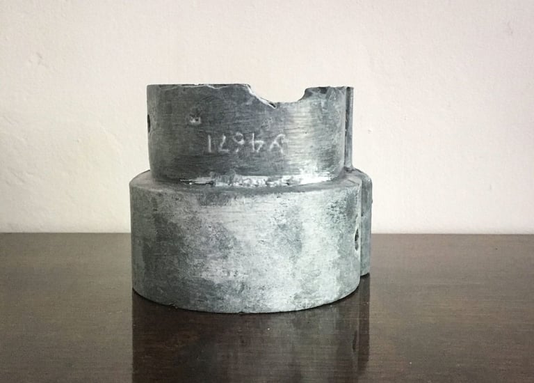 Faux lead painted pipe connector resembling a modern sculpture on a table