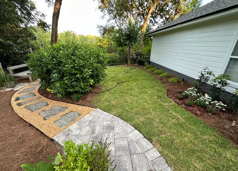 a walkway with a stone path leading to a bench