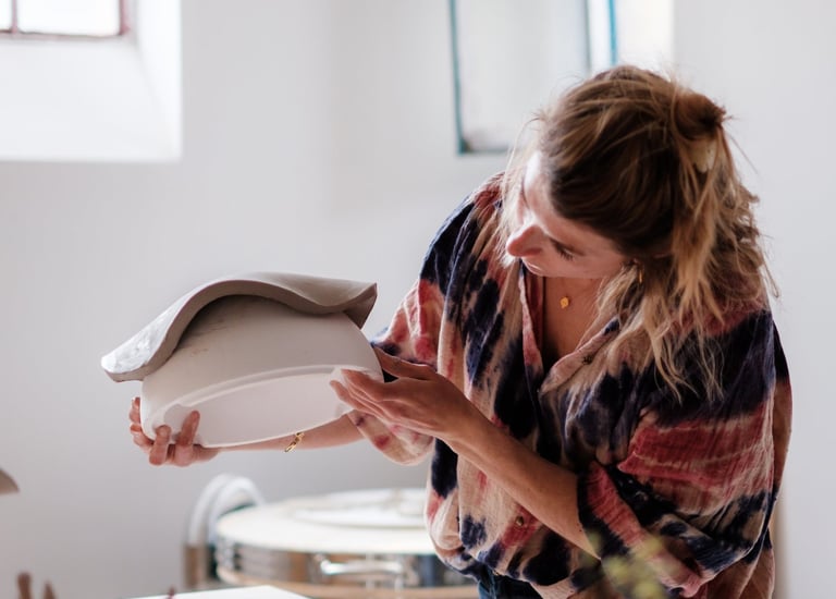 Une femme artisane qui regarde sa création en céramique dans son atelier