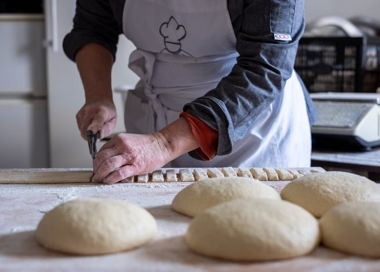 Une boulangère artisanale qui coupe sa pâte à pain