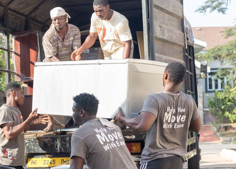 Four professional movers from TE Transporter Express collaborate to lift a large white chest freezer