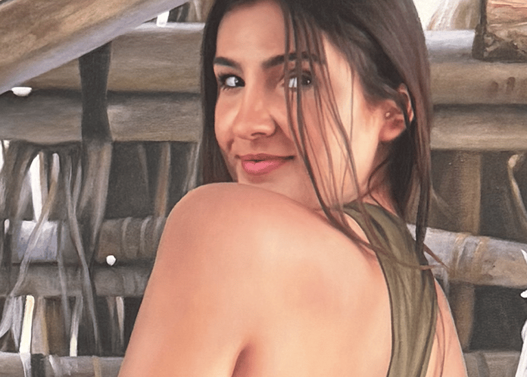 Realistic portrait drawing of a smiling woman looking over her shoulder against a rustic wooden background.