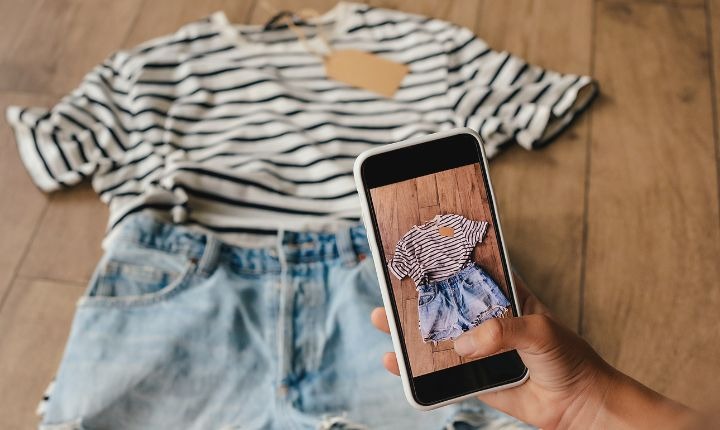 Persona tomando una foto de playera a rayas y shorts de mezclilla con un smartphone para revenderlos