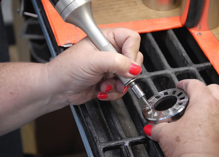 A technician performs precision metal deburring on a circular industrial component using a pneumatic handheld tool.
