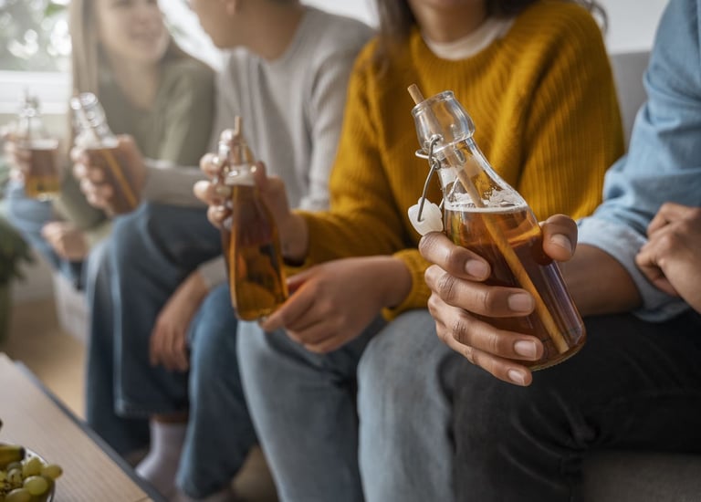Un grupo de amigos sosteniendo botellas de vidrio con kombucha orgánica.