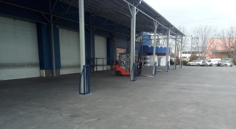 Red forklift parked under a covered loading dock at an industrial warehouse facility.