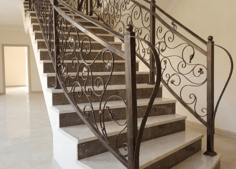 Elegant marble staircase featuring custom wrought iron handrails with decorative scrollwork.