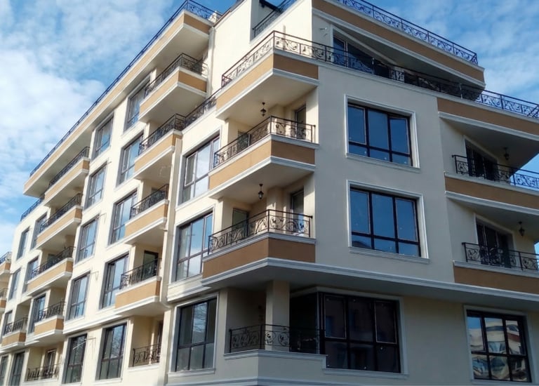 Modern luxury apartment building with balconies and wrought iron railings under a blue sky.