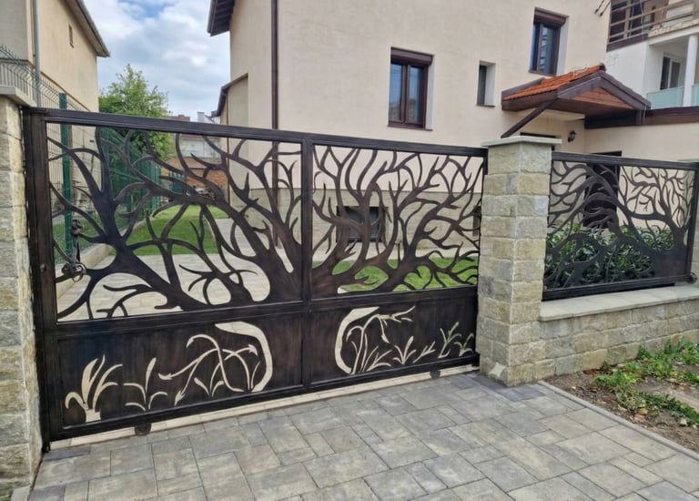 Custom decorative wrought iron sliding gate with an intricate laser-cut tree design for a residential driveway.
