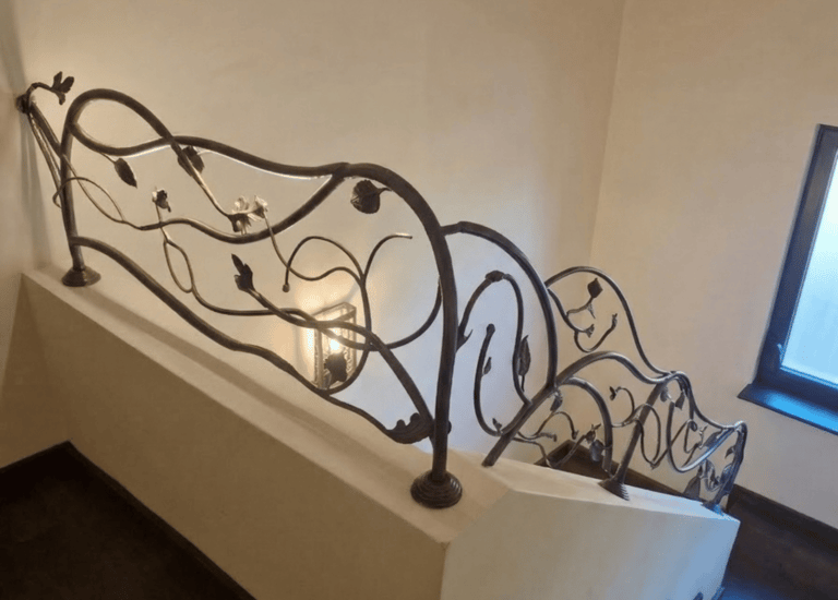 Custom wrought iron staircase railing with decorative leaf and vine patterns on a modern wooden staircase.