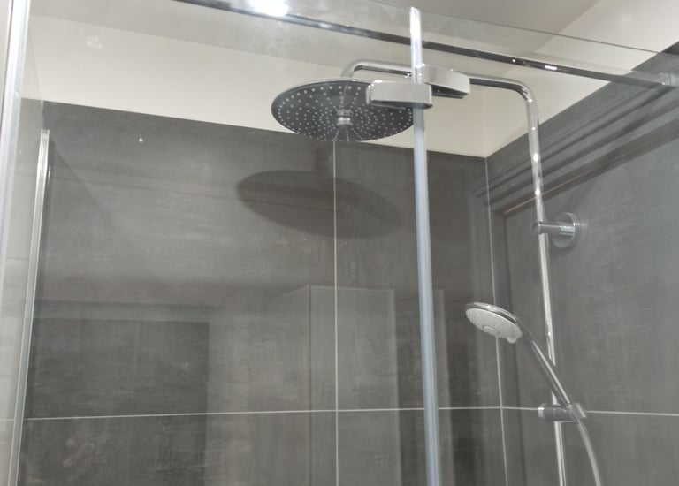 Douche de salle de bain moderne avec grande tête de pluie et douchette à main sur carrelage gris fon