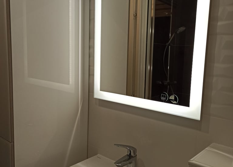 Salle de bain moderne avec miroir carré rétroéclairé LED au-dessus d'une vasque en céramique blanche