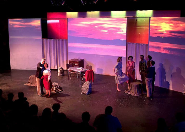 A group of young adults in a staged hiking scene. Vivid sunsets are on screens behind them.