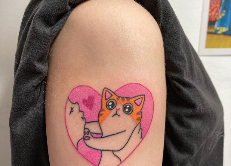 a cat with a heart shaped tattoo on the arm
