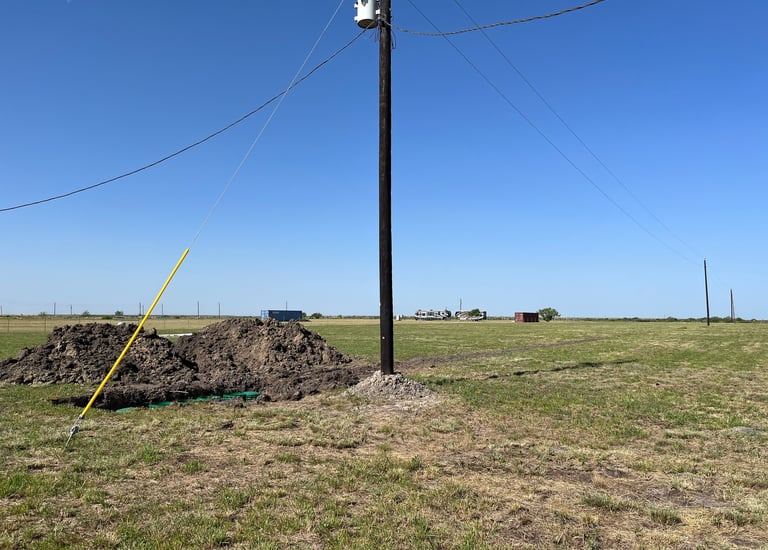 a pile of dirt in a field with a power pole installed nearby