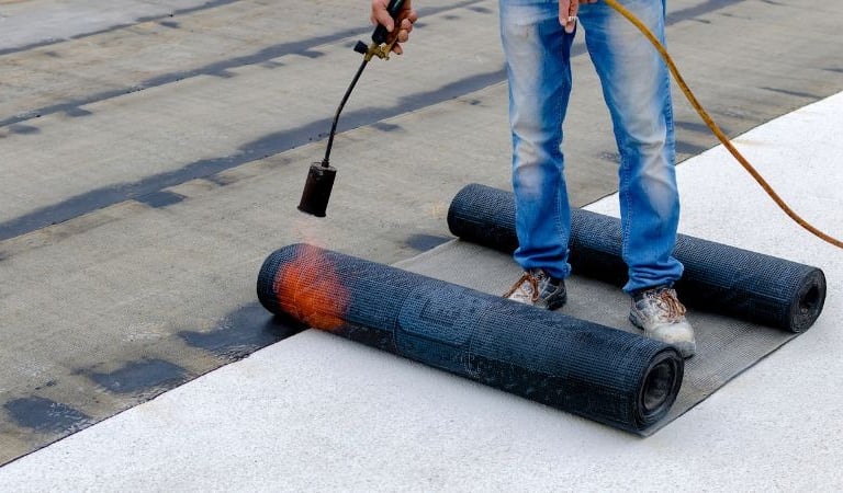 a man is using a hose to remove a black paint on a concrete floor