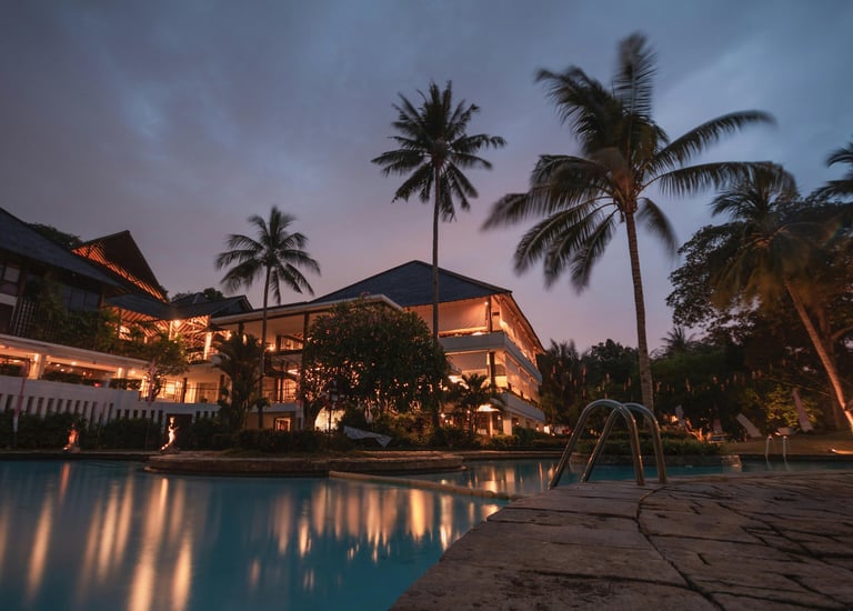 ein Pool und Palmen im Hintergrund ein Hotel