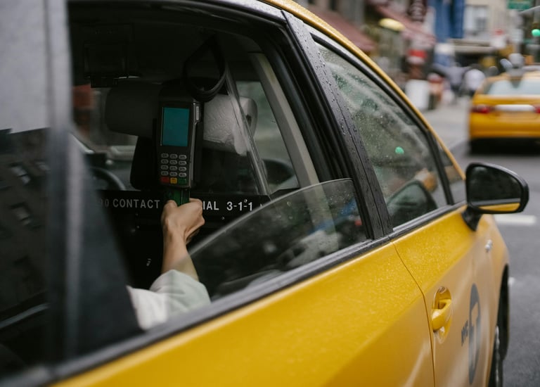 Eine Person fährt in einem Taxi in einer Stadt und bezahlt mit ihrer Kreditkarte