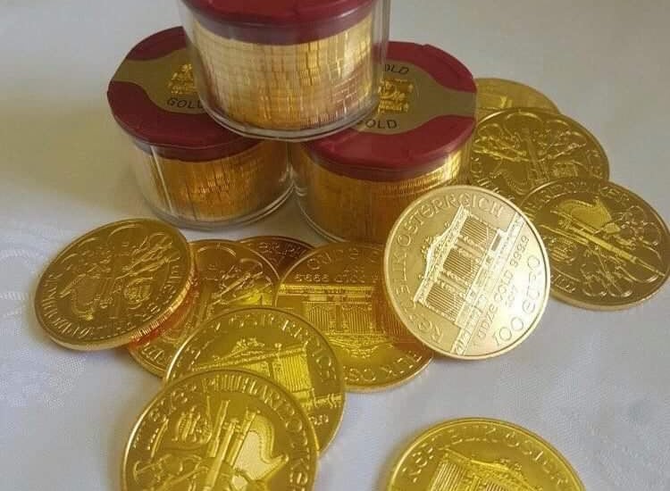 kopka zlatych minci na stole i v krabicke
