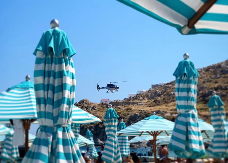 a helicopter flying over a beach with umbrellas