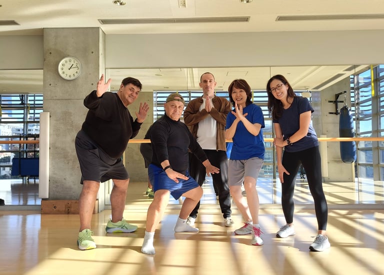 Heng Hu and workshop attendees smiling and posing in a brightly lit fitness studio with wood floors
