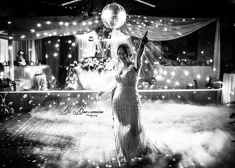 Mariée en robe sirène dentelle lors de l’ouverture de bal, fumées et boule à facettes N&B.