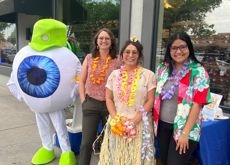 Smiling people with the Edge Optics' eyeball mascot with hula accents