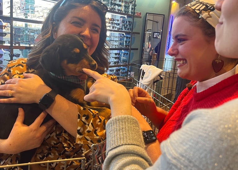 Smiling people holding a puppy for Edge Optics' community pet adoption event