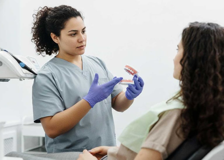 Dentista explicando a paciente sobre las protesis dentales, sosteniendo una protesis dental