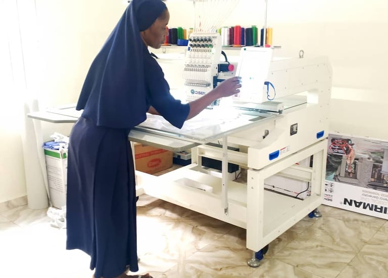 A nun operating a professional computerized industrial embroidery machine in a garment workshop.