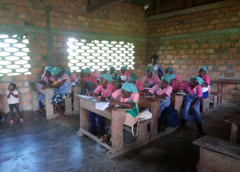 Students in pink and blue uniforms study in a brick classroom during a rural community education session.