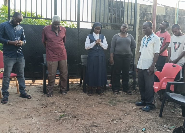 A group of people and a Catholic nun standing outdoors for a community prayer gathering.