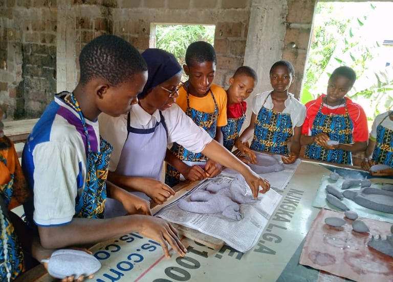 Students in a workshop learning clay modeling and sculpture techniques with a teacher.